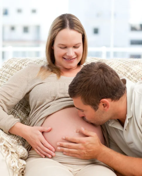 Orgoglioso uomo baciare la pancia della sua ragazza incinta seduta i — Foto Stock
