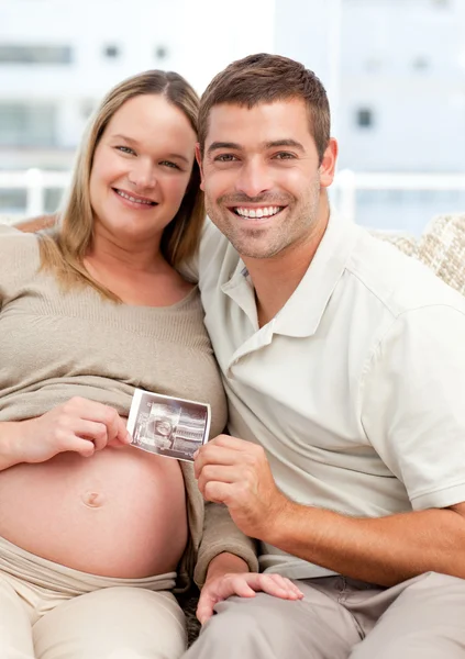 Orgulhoso futuro mãe e pai mostrando uma ecografia para a câmera — Fotografia de Stock