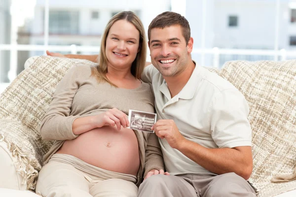 Fröhliches Paar zukünftiger Eltern mit einem Echo — Stockfoto