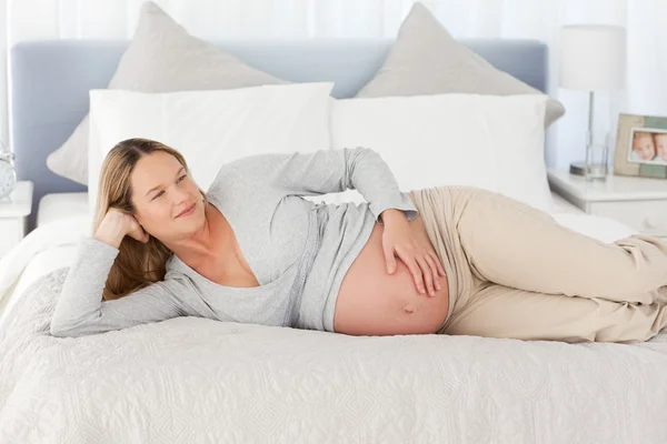 Pensiva futura mamma sdraiata su un letto — Foto Stock