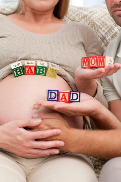 Close up of future parents holding cubes forming the words mom , — Stock Photo, Image