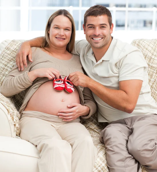 Lovely couple putting baby shoes on the woman's belly — Stock Photo, Image