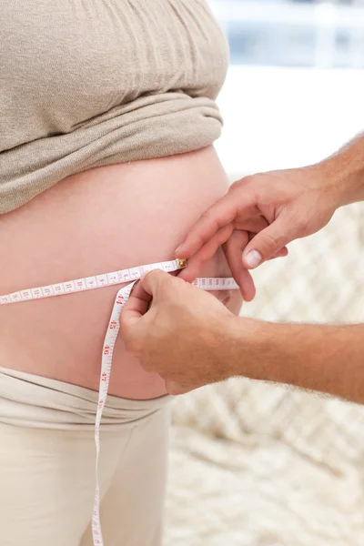 Acercamiento de un hombre midiendo el vientre de su esposa embarazada — Foto de Stock