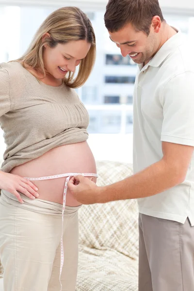 Внимательный мужчина измеряет талию беременной жены — стоковое фото