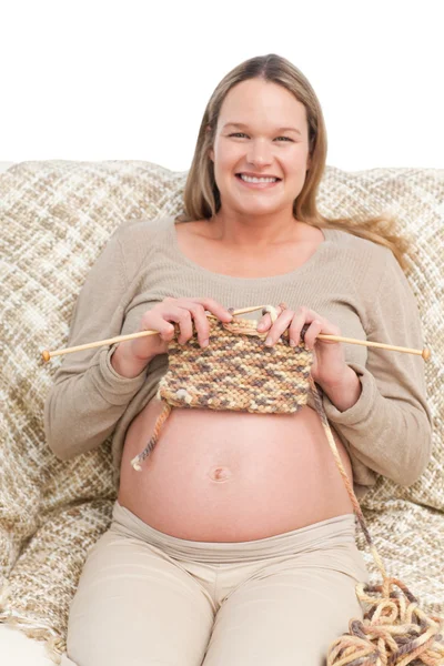 ソファーに座って編み物うれしそうな妊娠中の女性 — ストック写真