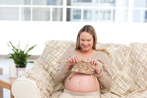 Glückliche Schwangere strickt im Wohnzimmer — Stockfoto