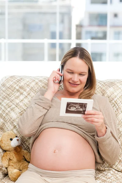 Szczęśliwa kobieta w ciąży patrząc na USG a dzwoniąc — Zdjęcie stockowe
