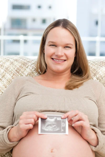 Sorrindo futura mãe mostrando uma ecografia para a câmera — Fotografia de Stock