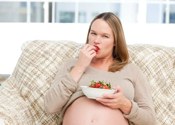 Śmieszne przyszłych mama jeść truskawki odpoczynku na kanapie — Zdjęcie stockowe