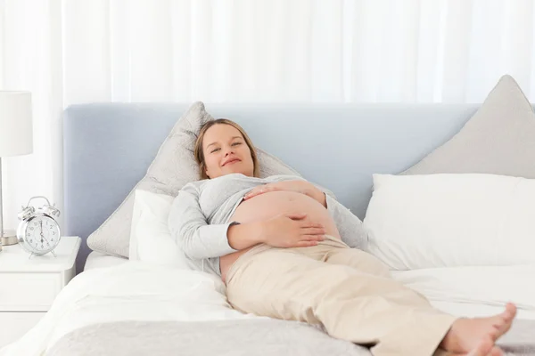 Χαμογελώντας έγκυος γυναίκα χαλαρώνοντας σε ένα κρεβάτι — Φωτογραφία Αρχείου
