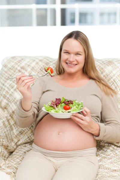 Mujer embarazada alegre comiendo verduras — Foto de Stock