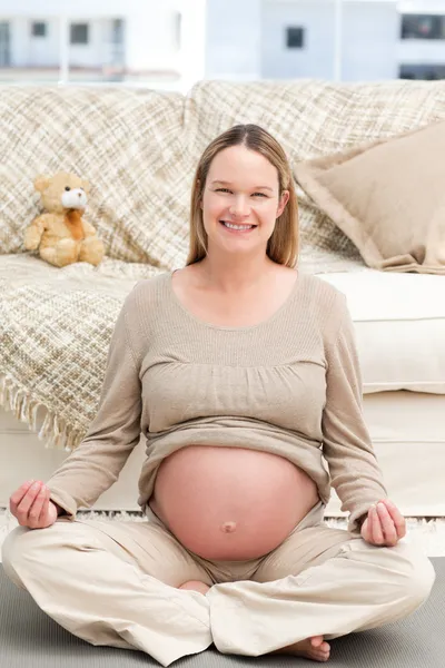 Schöne schwangere Frau macht Yoga sitzend auf dem Boden — Stockfoto