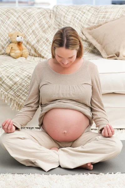 Donna incinta caucasica che fa yoga sul pavimento — Foto Stock