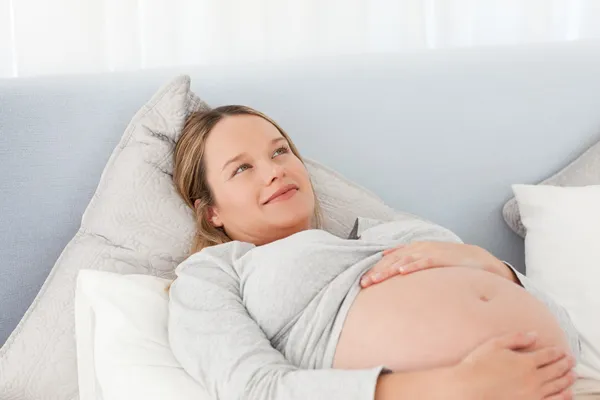 Mulher grávida pensativa descansando em uma cama — Fotografia de Stock