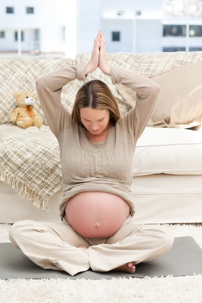 Беременная женщина занимается йогой на полу в своей гостиной — стоковое фото