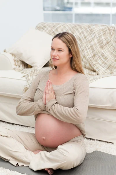 Focalizzato futura madre facendo esercizi di yoga sul pavimento — Foto Stock