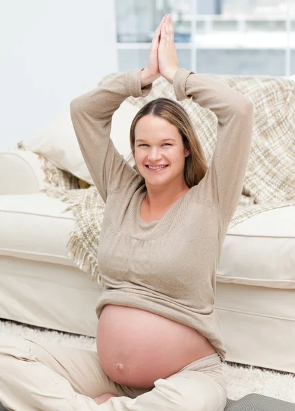 Encantadora mulher grávida fazendo exercícios de ioga no chão — Fotografia de Stock
