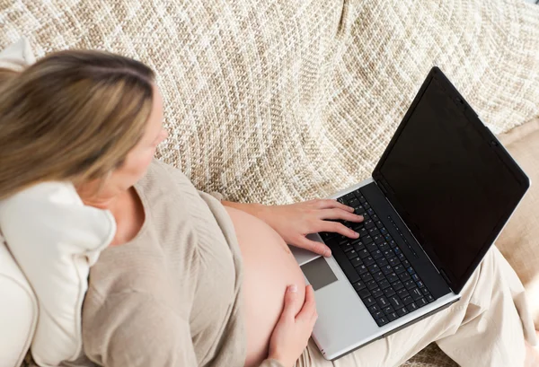 Κάτοψη του μια μελλοντική μαμά χρησιμοποιώντας το laptop της στον καναπέ — Φωτογραφία Αρχείου