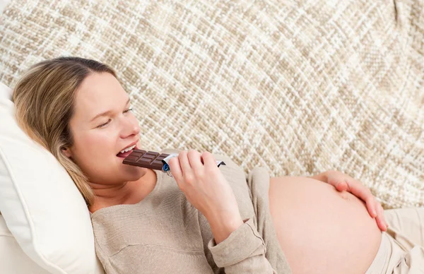 Rozkošný prgnant žena, pojídání čokolády při relaxaci — Stock fotografie