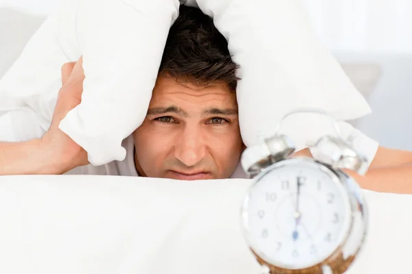 Alarm saatini bekleyen yastık altına ile üzgün bir adam — Stok fotoğraf