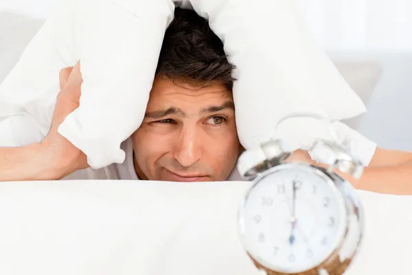 Handsome man putting his head under the pillow — Stock Photo, Image