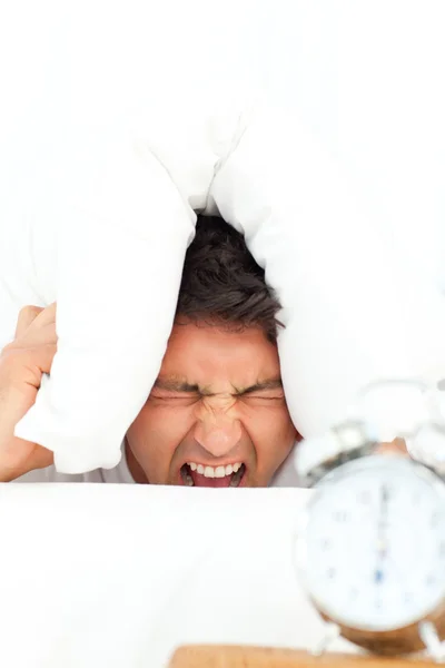 Homem estressado por seu despertador colocando sua cabeça sob o pelotão — Fotografia de Stock