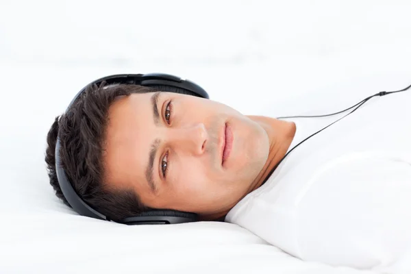 Charismatic man listening music lying on his bed — Stock Photo, Image