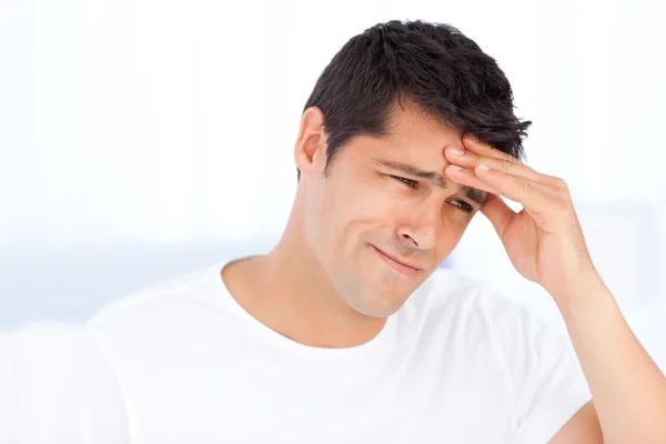 Homem preocupado tendo uma dor de cabeça sentado em seu quarto — Fotografia de Stock