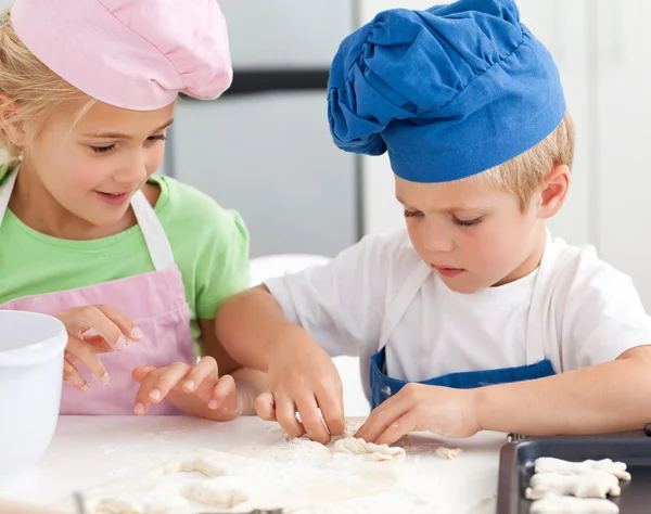 Yngre bror och syster knåda en deg att göra kakor — Stockfoto