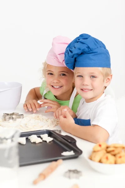 Dois pequenos chefs preparando biscoitos na cozinha — Fotografia de Stock