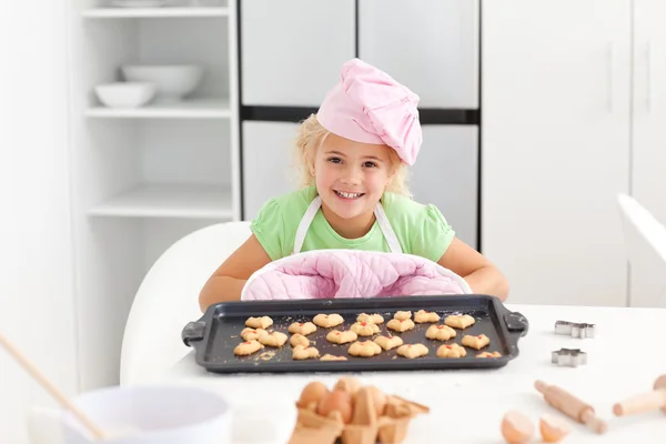 Glad liten flicka som håller en tallrik med hennes redo att äta kakor — Stockfoto