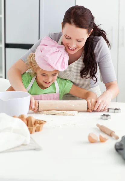 Belle mère et sa fille mignonne en utilisant un rouleau à pâtisserie — Photo