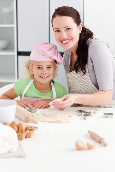 Portrait of a happy mother and daughter kneading a dough — Stock Photo, Image