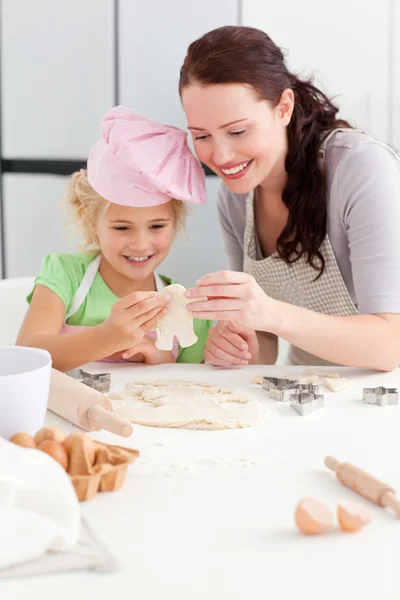 Vrolijke moeder en dochter maken van cookies in de vorm van een man — Stockfoto