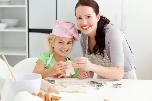 Cute daughter and mother showing a cookie in form of a man — Stock Photo, Image