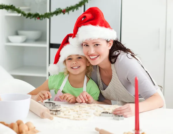 Ritratto di una ragazza carina con sua madre che cuoce i biscotti di Natale — Foto Stock
