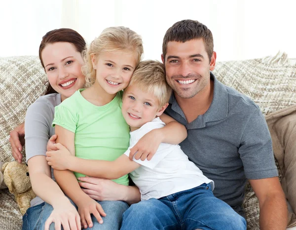 Sevimli aile kanepede oturan ve gülümseyerek — Stok fotoğraf