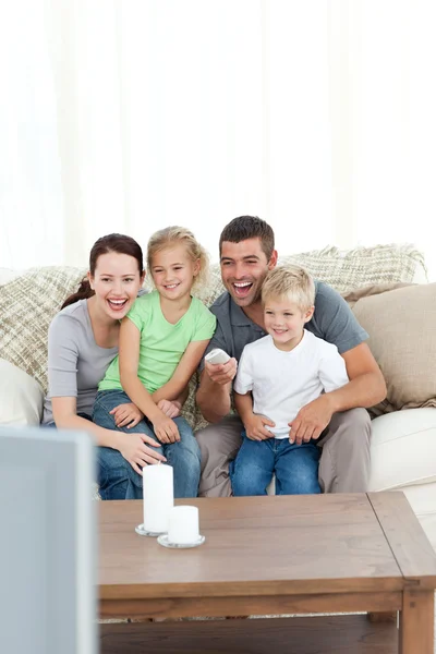 Glückliche Familie lacht, während sie vor dem Fernseher sitzt — Stockfoto