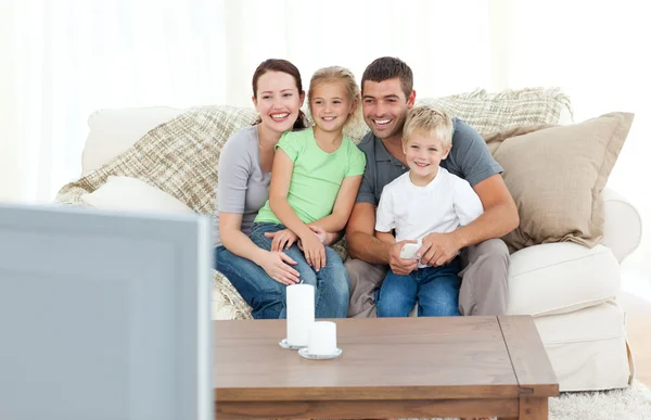 Прекрасная семья смотрит телевизор вместе, сидя на диване — стоковое фото