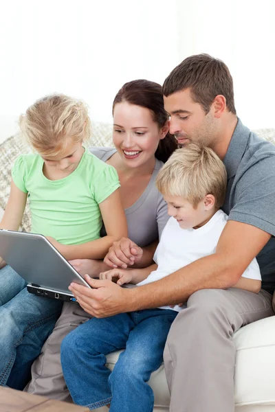 Los padres y los niños que usan su computadora portátil juntos sentados en el — Foto de Stock