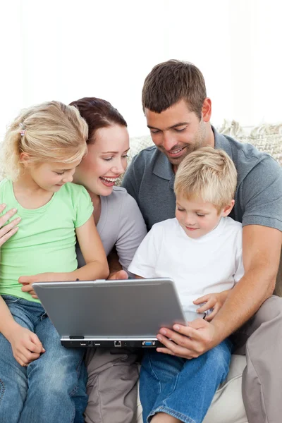 Adorável família trabalhando juntos em um laptop sentado no sofá — Fotografia de Stock