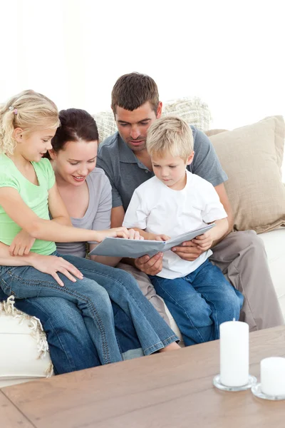 Счастливая семья смотрит на фотоальбом, сидя вместе в зале. — стоковое фото