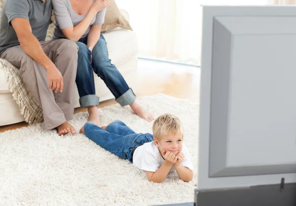 Внимательный маленький мальчик смотрит телевизор, лежащий на полу — стоковое фото