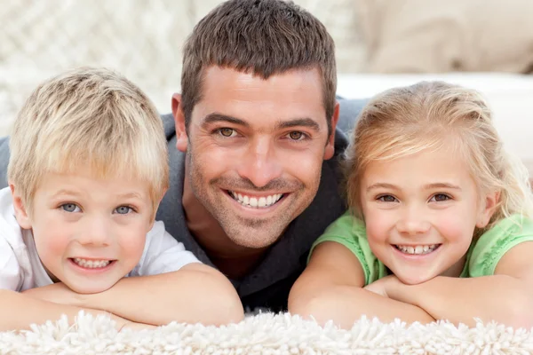 Kinderen en vader kijken naar de camera op de verdieping — Stockfoto
