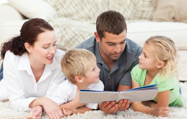 Familie schaut auf ein Buch auf dem Fußboden — Stockfoto