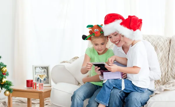 Mutter und Kinder schauen auf einen Kalender, der auf dem Sofa liegt — Stockfoto