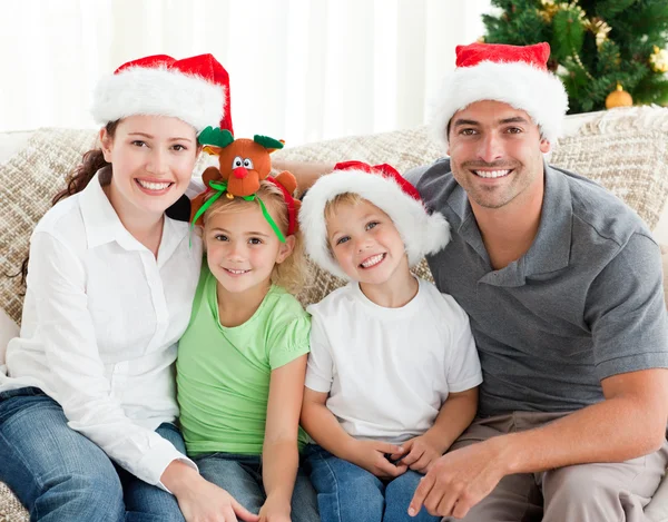 Retrato de una familia feliz con sombreros de Navidad sentado en el tan —  Fotos de Stock