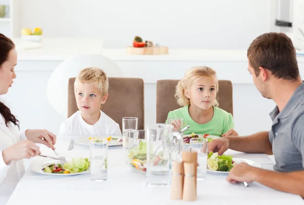 Familia seria comiendo una ensalada en el almuerzo en la cocina — Foto de Stock