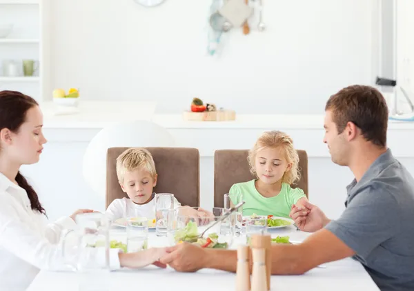 Rodzina razem modląc się przed jedzeniem ich sałatka na obiad — Zdjęcie stockowe