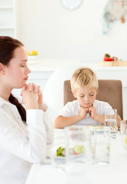 Geconcentreerde kleine jongen met zijn moeder bidden voor het eten van th — Stockfoto